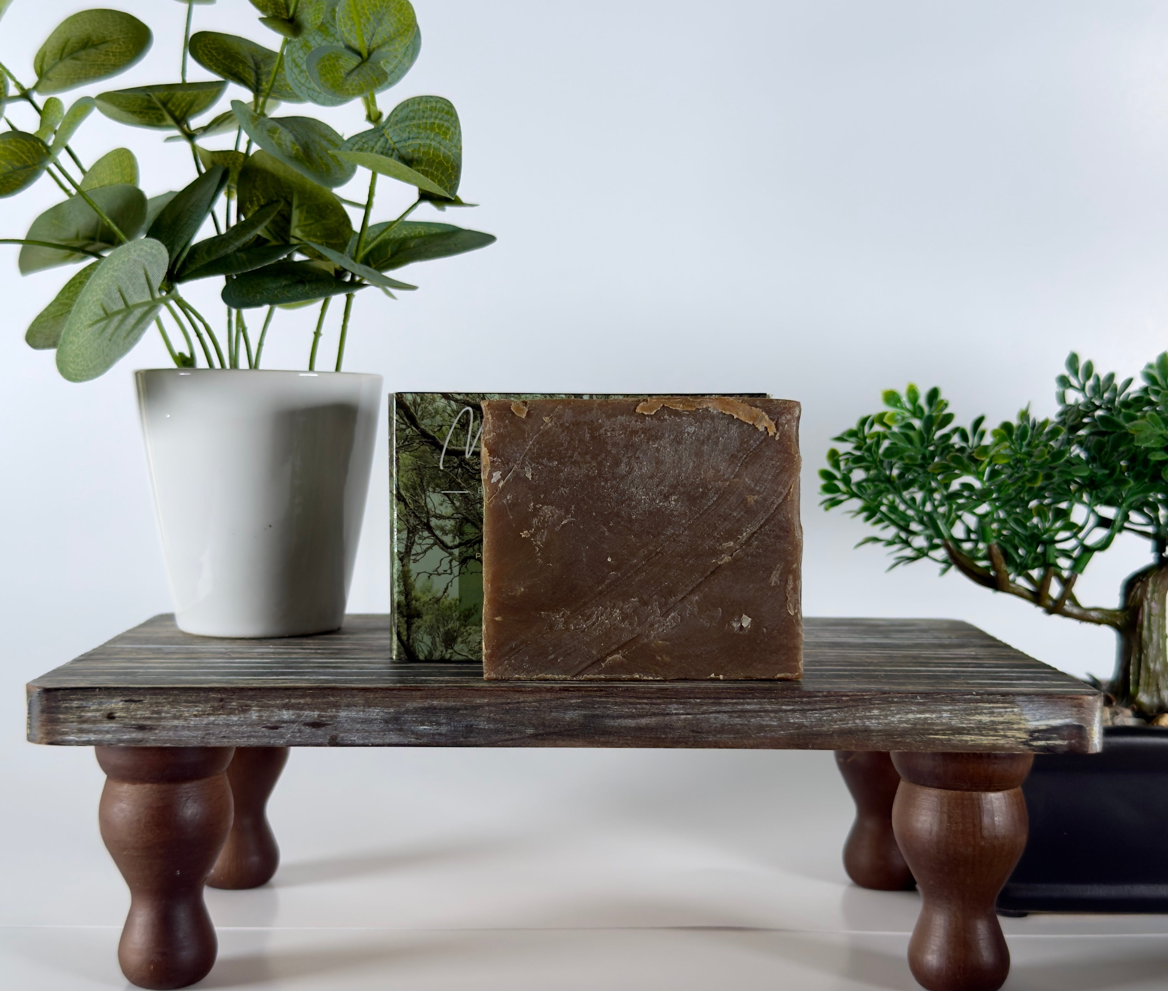 Wooden table with a plant and decorative items on a white background