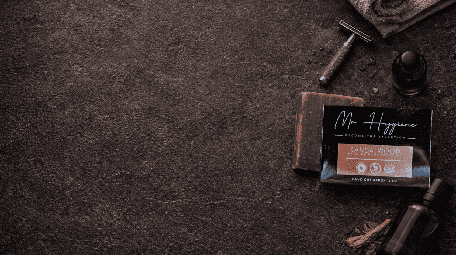 Shaving products including a razor, soap, and soap bar on a dark textured surface.