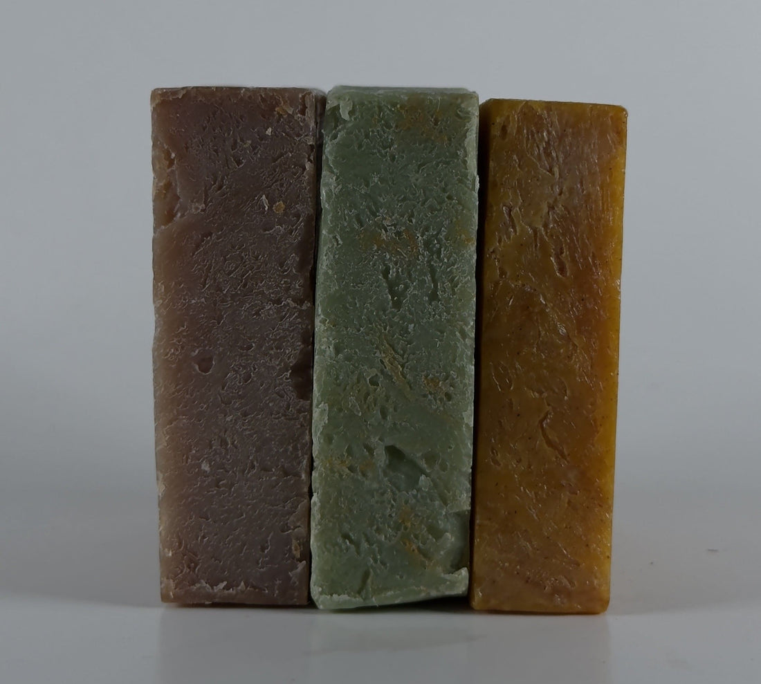 Three bars of different colored soap stacked against a gray background