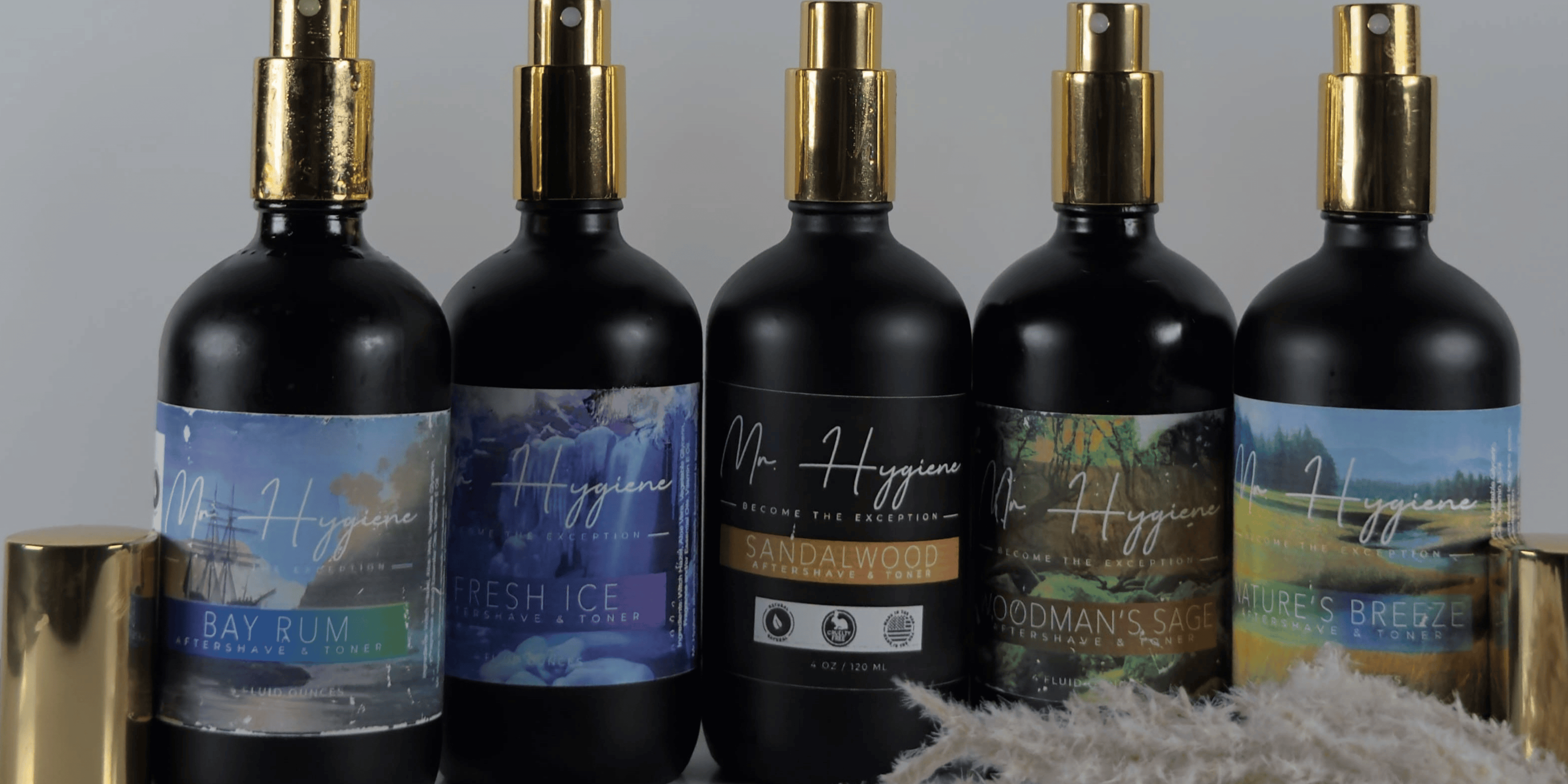 Five black spray bottles with colorful labels on a gray background