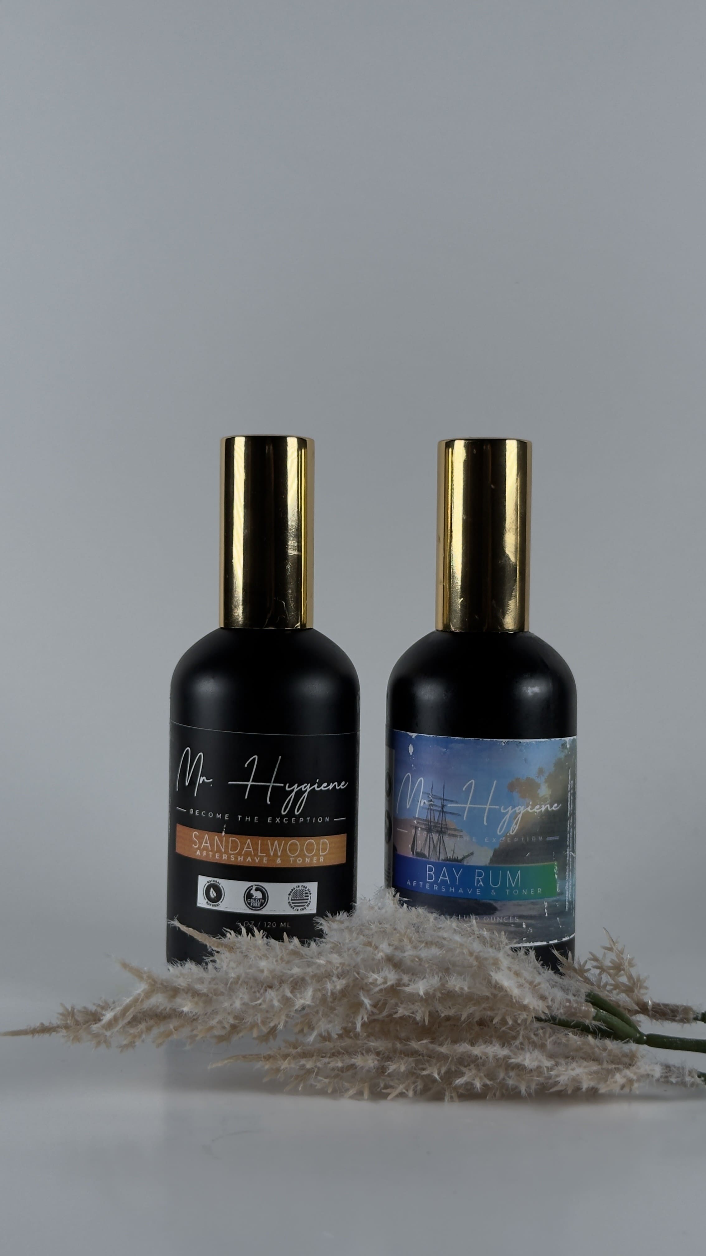 Two black bottles with gold caps on a gray background