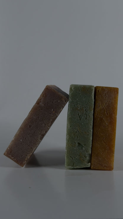 Three bars of soap in different colors stacked on a gray background