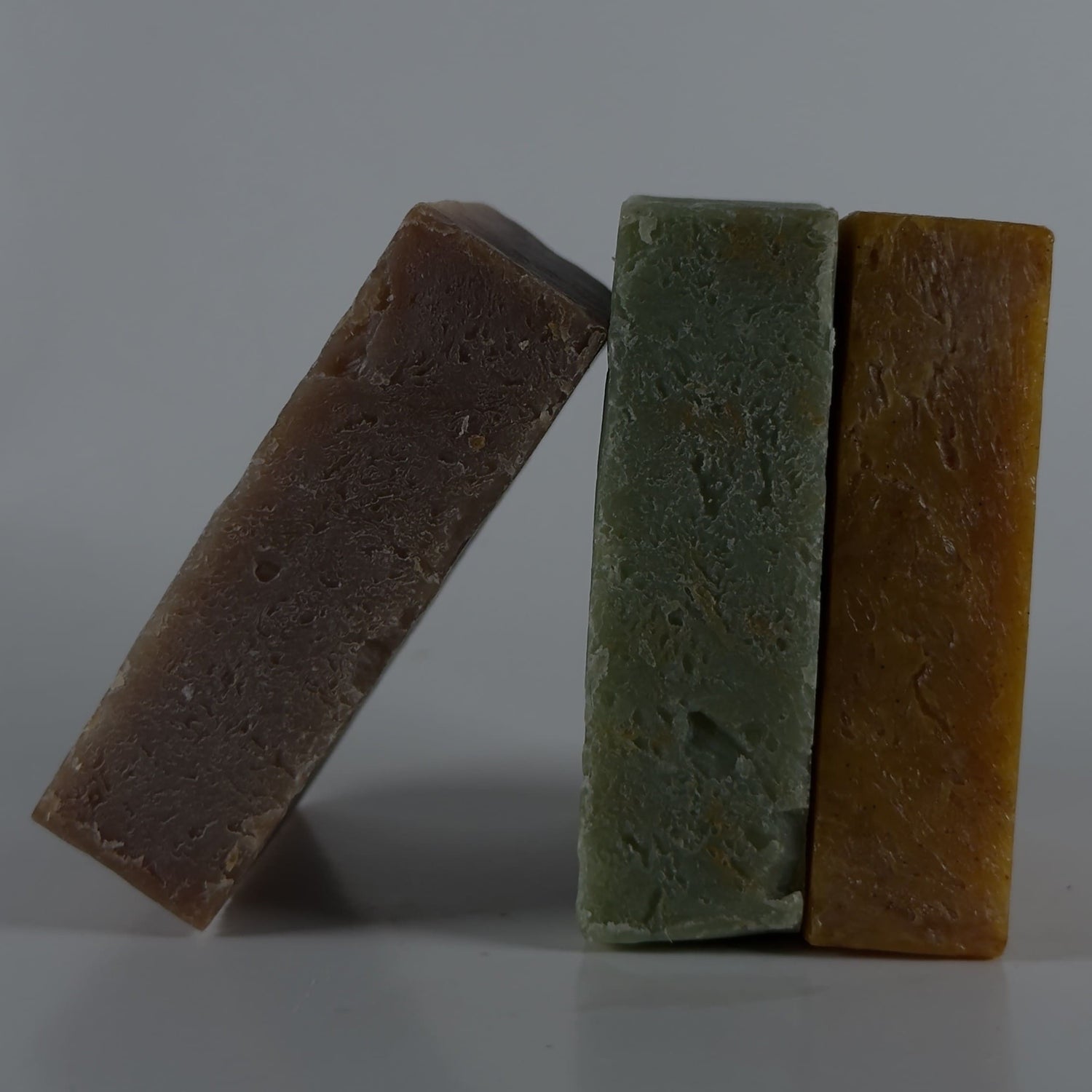 Three bars of soap in different colors stacked on a gray background