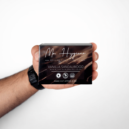 Hand holding a box of Mr. Hygiene Vanilla Sandalwood soap against a white background